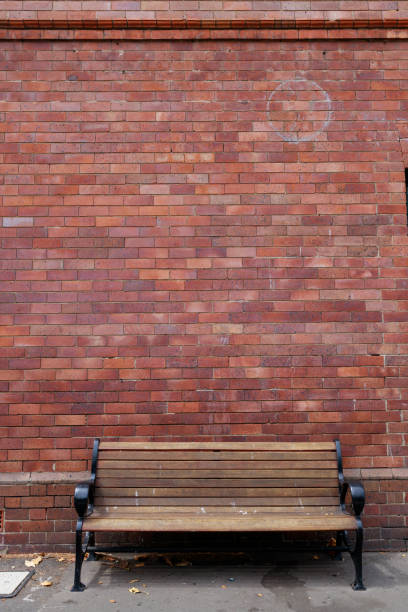 istock Wooden bench against a red brick wall 1199634411