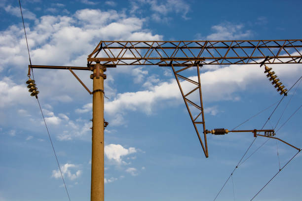 Electrification railway contact. High-voltage power line. Blue cloudy sky.