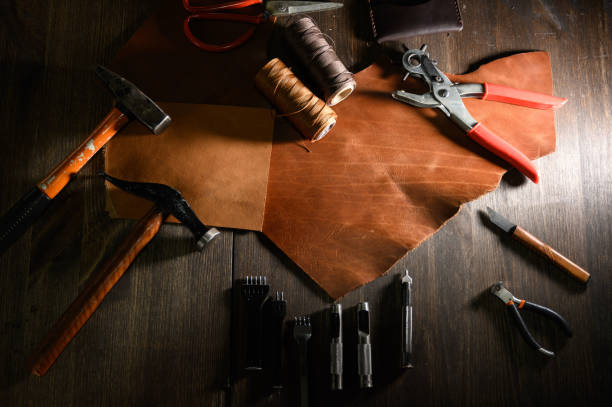 istock Leather craft or leather working. Leather working tools and cut out pieces of brown leather on craftman's work desk . 1199639967