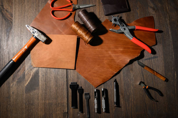 istock Leather craft or leather working. Leather working tools and cut out pieces of brown leather on craftman's work desk . 1199640026