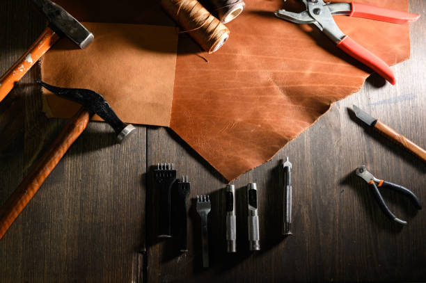 istock Leather craft or leather working. Leather working tools and cut out pieces of brown leather on craftman's work desk . 1199640027