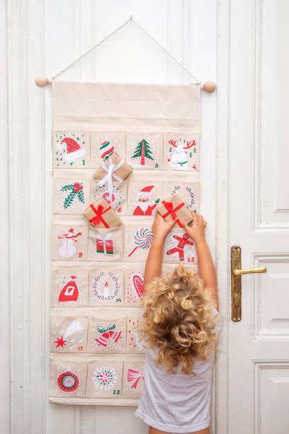 Il ragazzo apre un regalo dal calendario dell'Avvento - foto stock