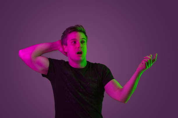 istock Caucasian man's portrait isolated on purple studio background in neon light 1199641789