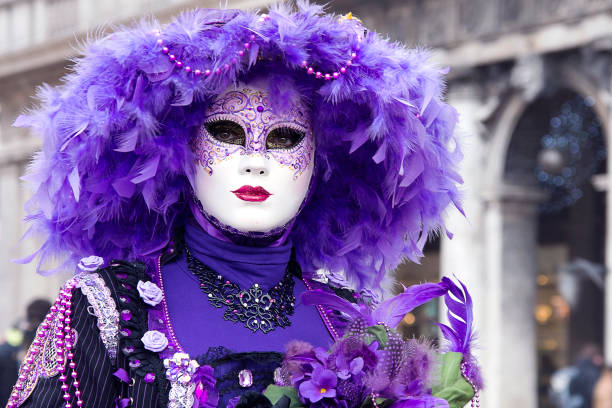 Venice, Italy - February 28, 2014. A woman wearing carnival costume and mask posing for casual photographers in St.Mark's Square