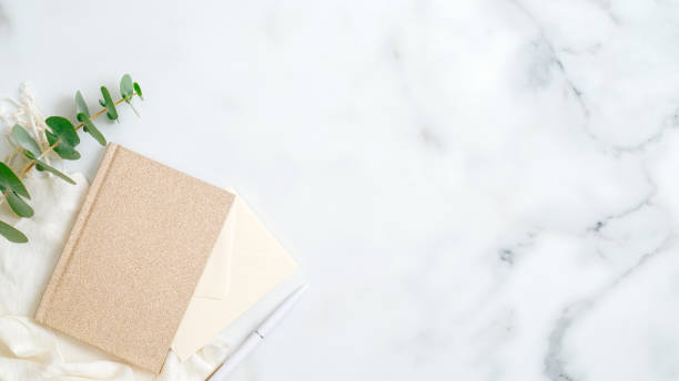 istock Cozy home office desk table with paper notebook, pen, eucalyptus leaf on marble background. Top view, flat lay, copy space. Elegant feminine workspace with stylish accessories concept 1199642175