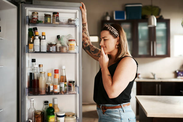 Hmm...what to make for dinner? Shot of a young woman searching inside a refrigerator at home refrigerator photos stock pictures, royalty-free photos & images