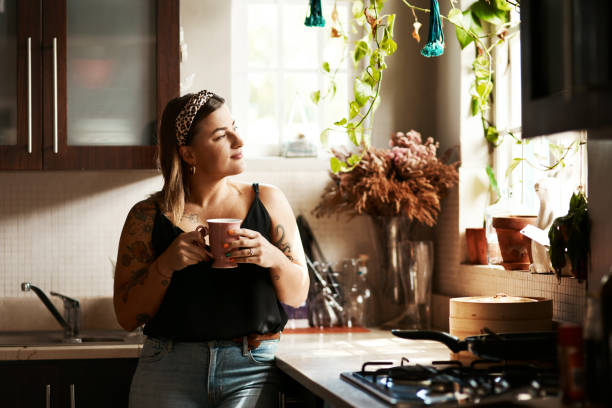 The road to relaxation is paved with coffee beans Shot of a young woman having a relaxing coffee break at home afternoon tea photos stock pictures, royalty-free photos & images