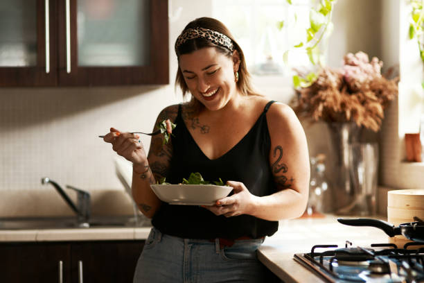 Is it really a diet if it tastes so good? Shot of a young woman eating a healthy salad at home vegan food photos stock pictures, royalty-free photos & images