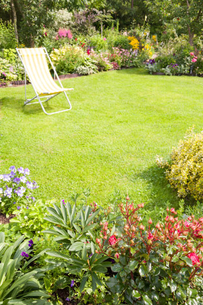 silla de jardín en un césped verde en un hermoso jardín de flores, vertical - chair grass flower bed nobody fotografías e imágenes de stock