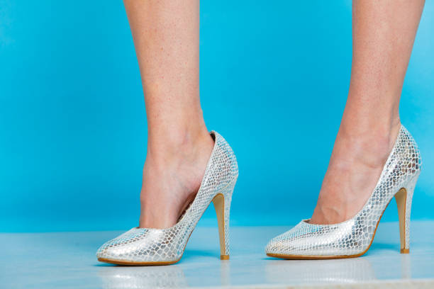 istock Female legs in silver high heels shoes 1199653586