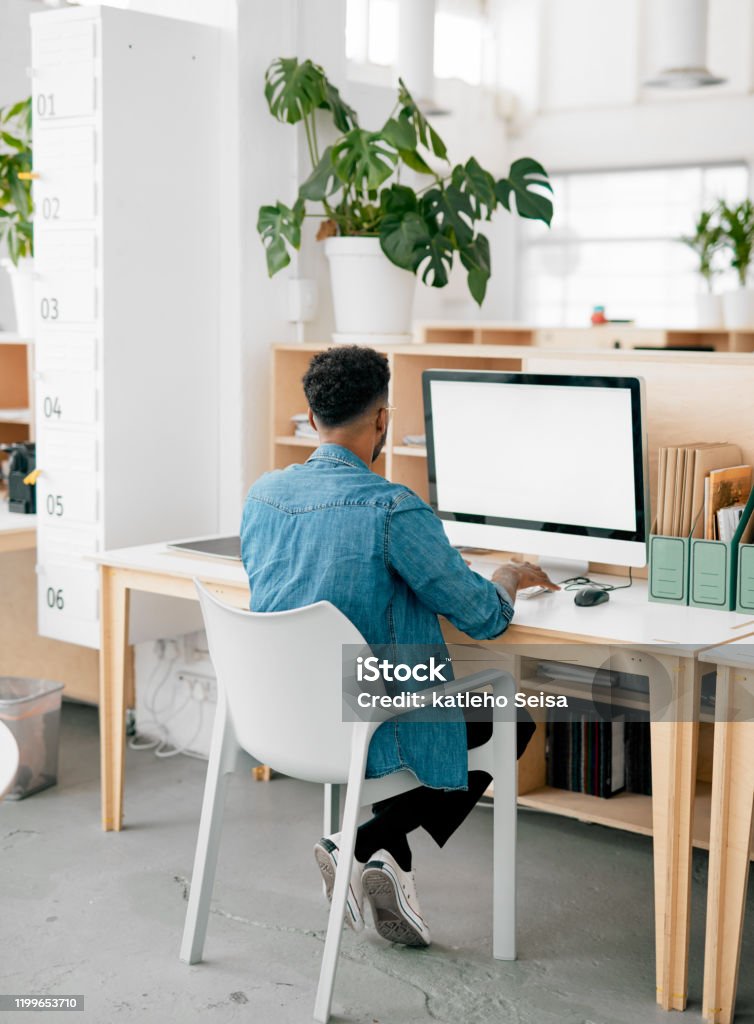 Great websites designed by the pro himself Shot of a young businessman using a computer in a modern office Desk Stock Photo