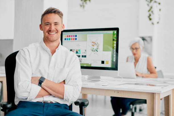 Portrait of a confident young businessman working at his desk with a colleague in the background