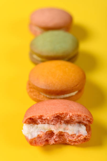 istock colorful macaroons and the front one with half eaten on yellow background 1199661246
