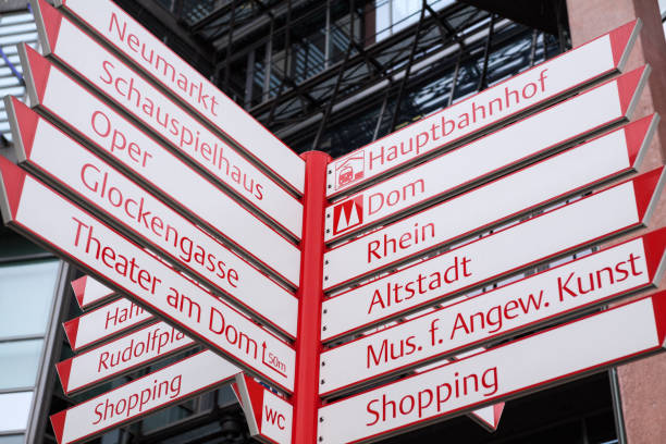 White and red colored arrows and fingerposts in Cologne near square Neumarkt with many directions and places named on arrows