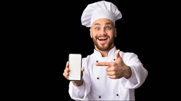 istock Cook Man Showing Phone Empty Screen Standing On Black Background 1199663330