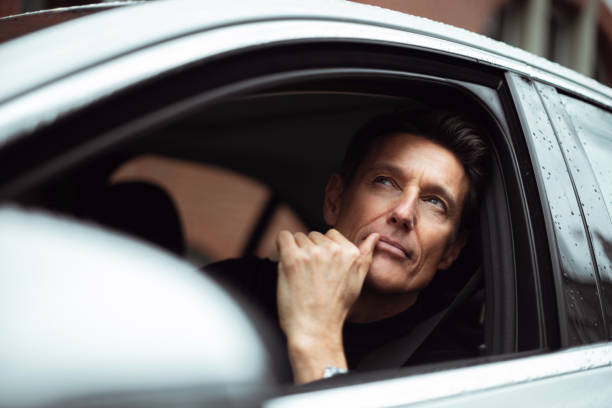On the right place Handsome 55-year-old man is looking through the window of his car. georgijevic frankfurt stock pictures, royalty-free photos & images