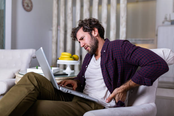 Tired man freelance worker stretch in sofa suffer from sitting long in incorrect posture, male employee have back pain or spinal spasm working in uncomfortable position. Sedentary life concept Tired man freelance worker stretch in sofa suffer from sitting long in incorrect posture, male employee have back pain or spinal spasm working in uncomfortable position. Sedentary life concept bad posture stock pictures, royalty-free photos & images