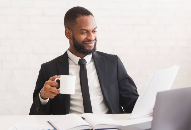 istock Cheerful businessman drinking coffe, reading daily reports 1199665400