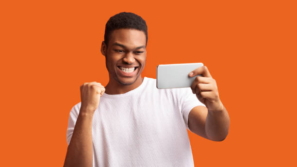 istock Excited afro guy using phone celebrating success 1199665422