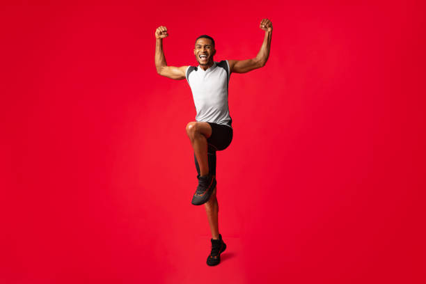 istock Full length afro guy celebrating triumph jumping at studio 1199666311