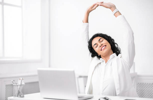 mexican manager stretching hands at work place - yoga business women indoors imagens e fotografias de stock