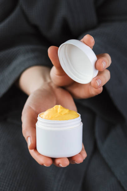 istock Woman holding opened plastic container with yellow cream in her hands, vertical mockup. 1199667271