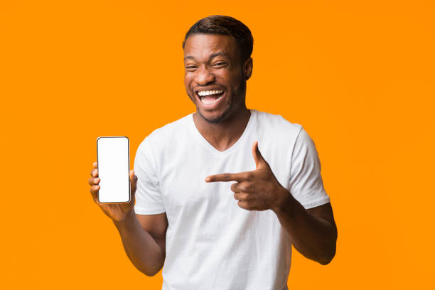 istock Guy Pointing Finger At Phone Screen Laughing, Orange Background, Mockup 1199667871