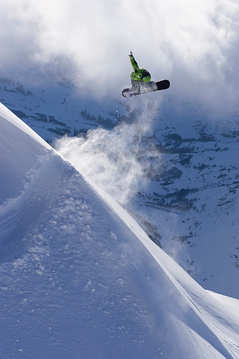 Snowboarder jumping in powder against a valley back drop.