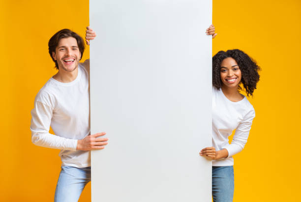 istock Happy Interracial Couple Holding Big White Advertisement Board 1199669813