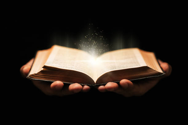 istock Man holds holy bible book on black background. 1199669954