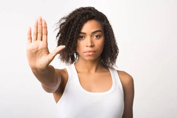 Photo of Black girl showing stop sign on white background