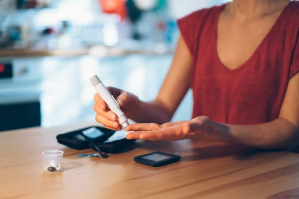 Diabetes blood sugar check Woman at home checking blood sugar levels with glaucometer easy test stock pictures, royalty-free photos & images