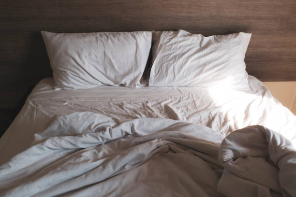 istock messy comfy white bed sheets and pillow life on Holiday . untidy unmade bed with white crumpled bed sheet and two messy pillows 1199671424
