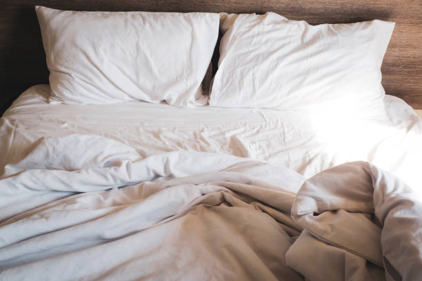 istock messy comfy white bed sheets and pillow life on Holiday . untidy unmade bed with white crumpled bed sheet and two messy pillows 1199671425