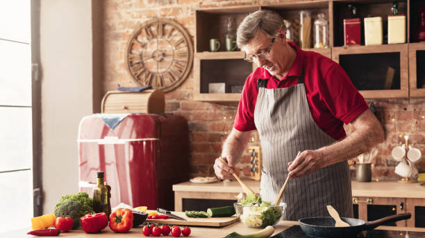 istock Caring grandfather preparing salad at home kitchen 1199671753