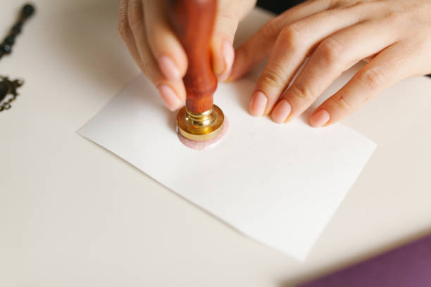 istock Holiday card in the making - wax stamp sealing on purple envelope 1199672191