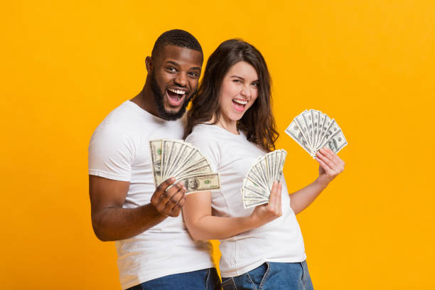 istock Overjoyed multiracial couple posing with bunches of dollars 1199675014