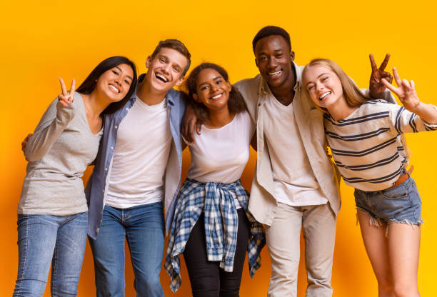 istock Group of multiracial students smiling and embracing over yellow background 1199675222