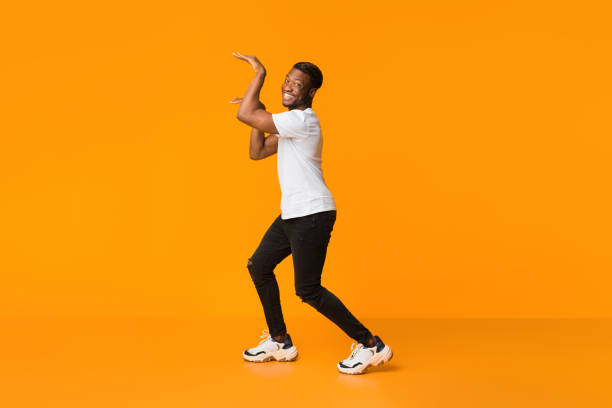 istock Black Guy Dancing In Egypt Style Having Fun, Orange Background 1199675568