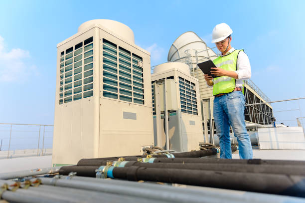 Engineer holding tablet  is checking the cooling tower on the roof of the building to be in good condition. Engineer holding tablet  is checking the cooling tower on the roof of the building to be in good condition. cooling rack photos stock pictures, royalty-free photos & images
