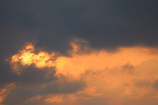 The sun is breaking through heavy, dark storm clouds, casting beams of light across the sky and illuminating the landscape below