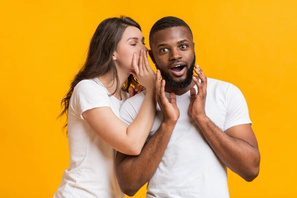 istock Young Woman Whispering Gossips Into Her Black Boyfriend's Ear 1199676607
