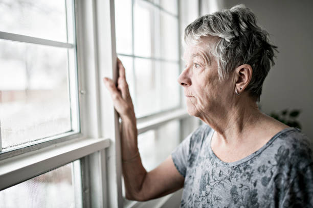 un triste solitario 70 años de edad senior en es apartamento - women depression window sadness fotografías e imágenes de stock