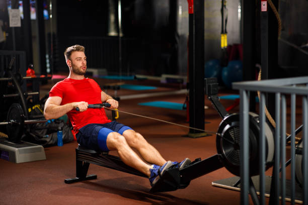 istock Young Muscular Fit Man using Rowing Machine at Gym 1199678219