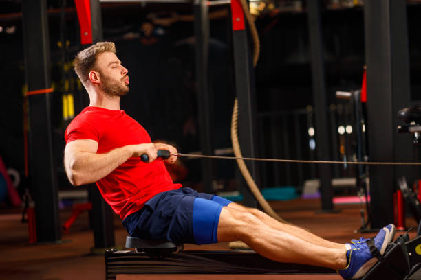 istock Young Muscular Fit Man using Rowing Machine at Gym 1199678351