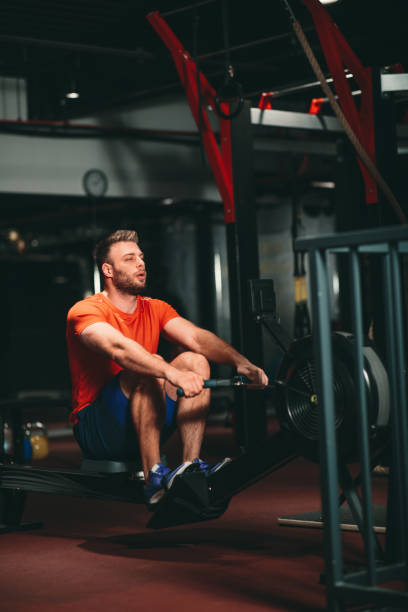 istock Young Muscular Fit Man using Rowing Machine at Gym 1199678416
