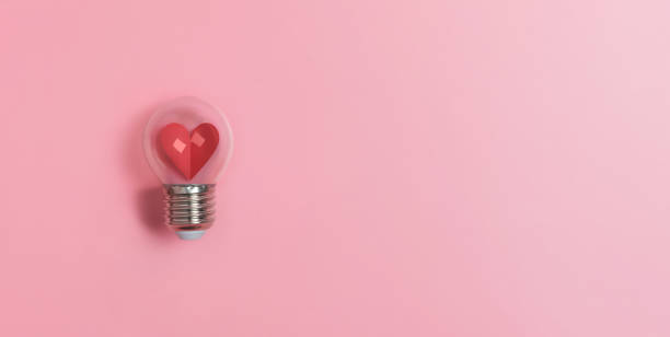 istock Red heart in light bulb on pink background with copy space. 1199678792