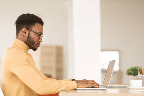 istock Afro guy working on his laptop at home 1199678813