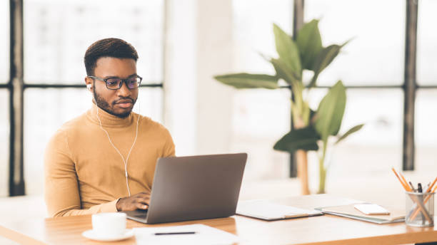 istock Concentrated afro guy in eyewear typing on keyboard 1199679679