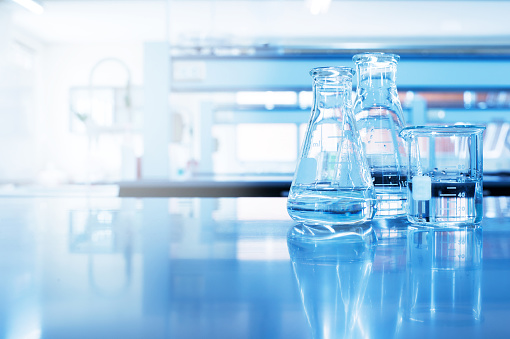 clear water in beaker and flask glass in chemistry blue science laboratory background